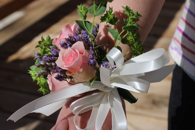 corsage with pink roses, purple flowers, and greenery